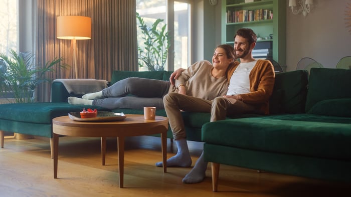 Folks sitting on the couch enjoying a movie.
