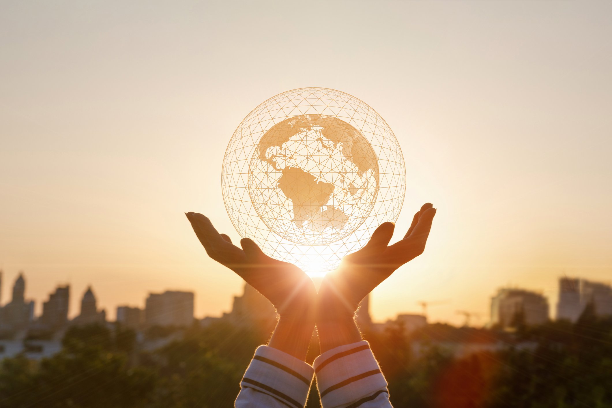 Hands holding a globe up to the sun signaling the dawn of a new era.