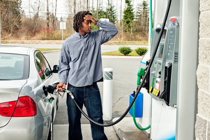 Person pumping gas with frustrated look on face.