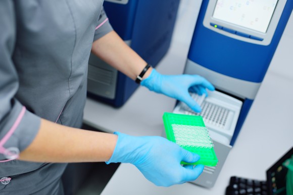A technician works with a diagnostic assay apparatus.