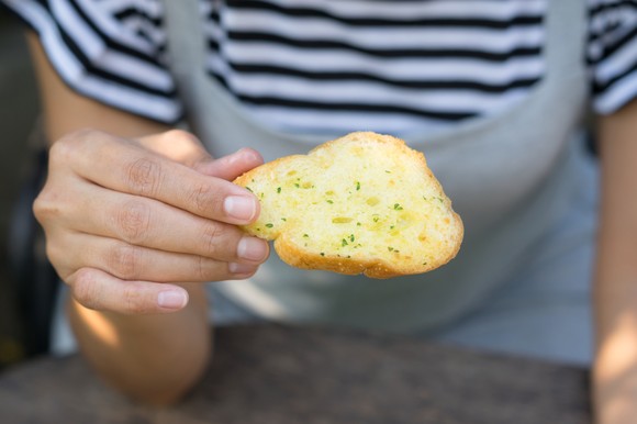 Person holding a piece of garlic bread.