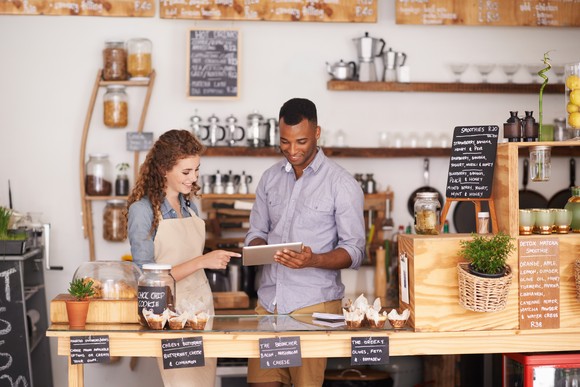 Two employees at a restaurant using a digital tablet.