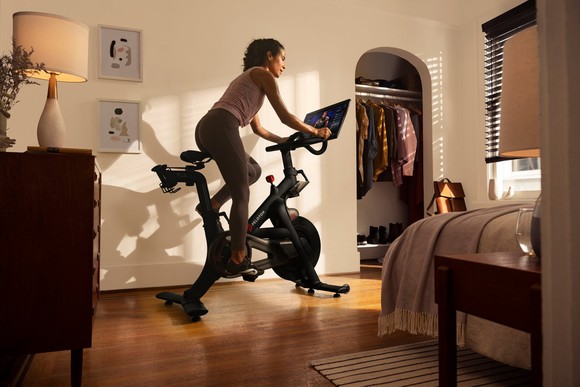 A person riding a Peloton exercise bike in their bedroom.