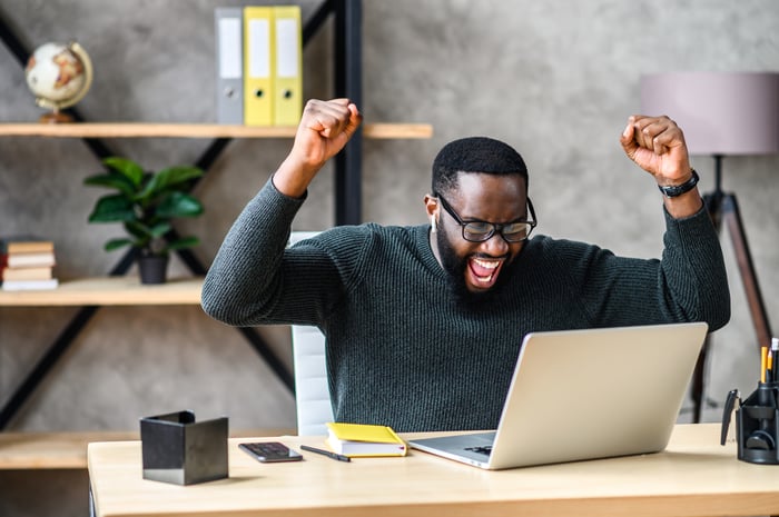 Person cheering looking at their laptop.