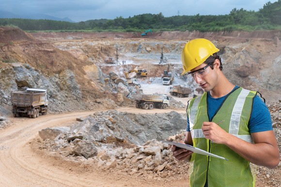 Miner wearing hard hat at an open pit mining operation.