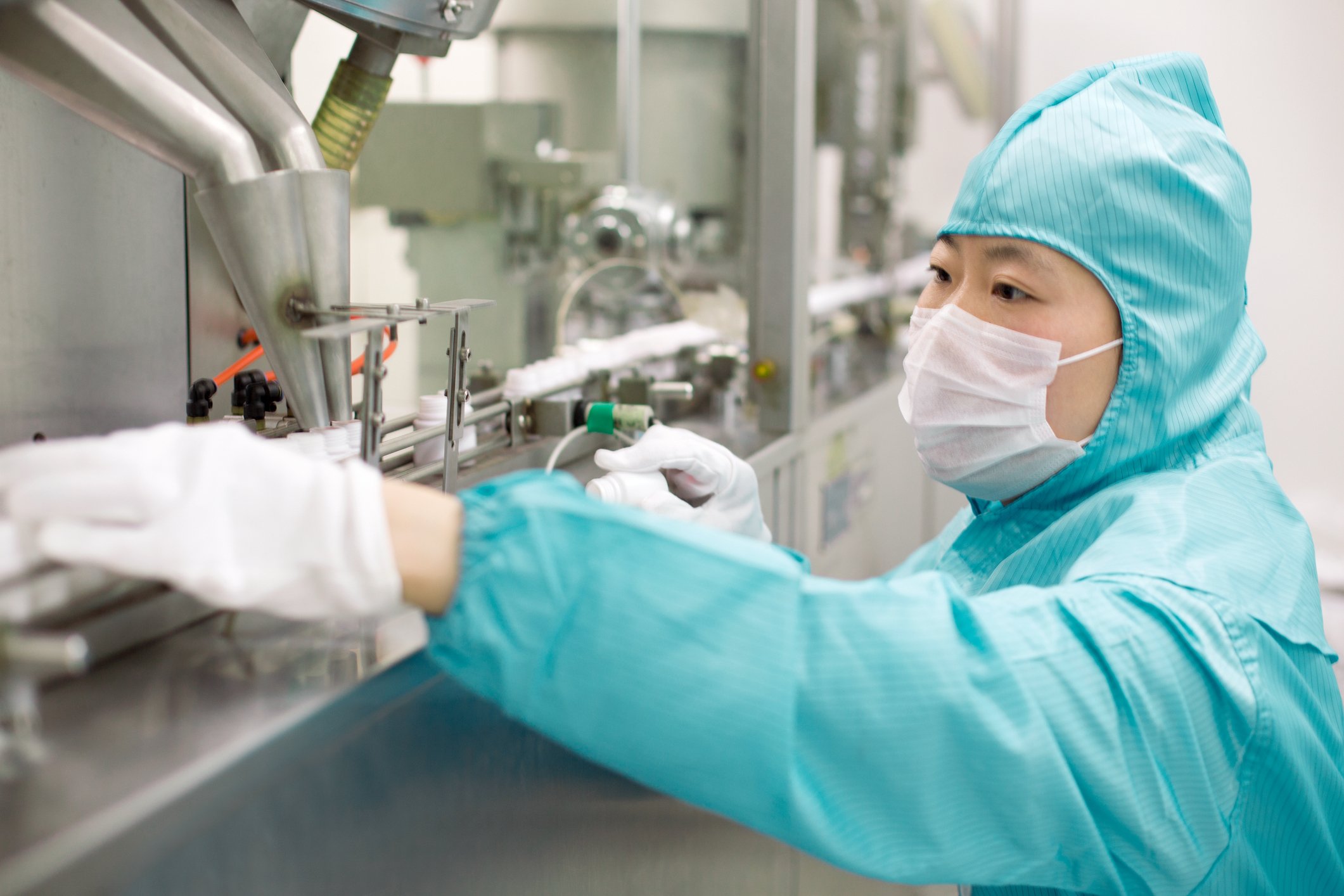 A pharmaceutical worker examines items on a medicine assembly line.