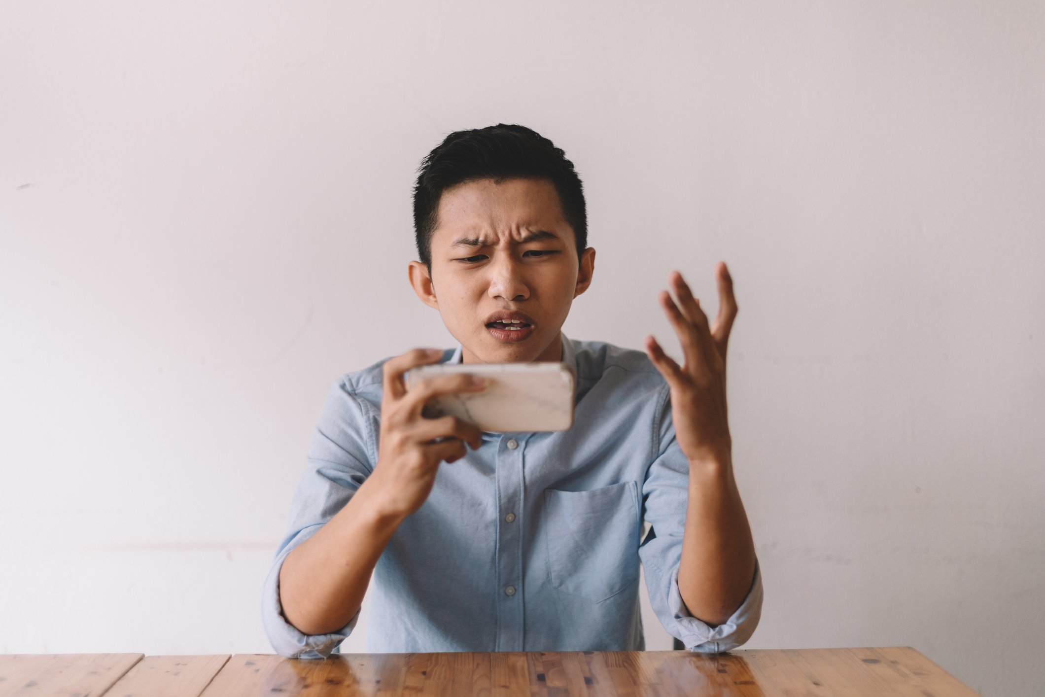 A person looks at their phone disappointedly while playing a mobile game.