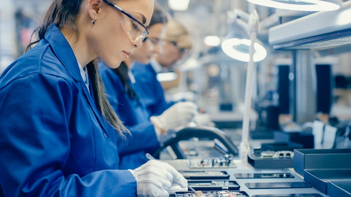 People are working on a mobile phone assembly line. 