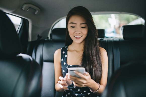 A passenger in a car checks a phone.