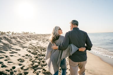 two people walking on the beach hugging