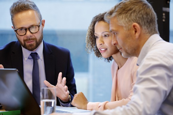 Three people talking and looking at computer.