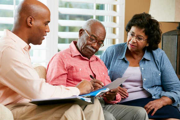 Three people look at documents.