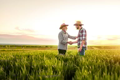 Two farmers shaking hands in a field