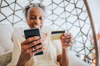 A person looking at a credit card and phone.