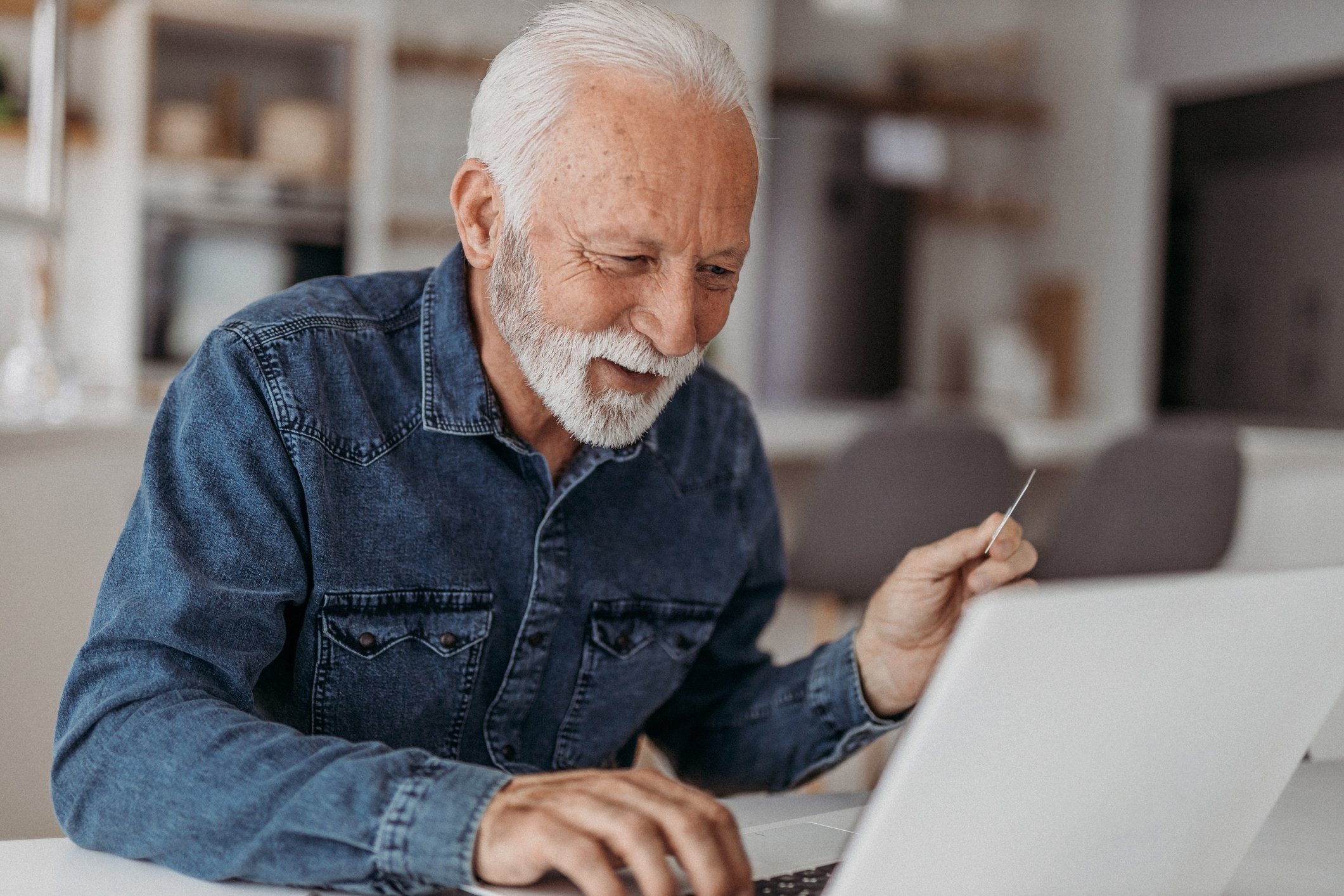 A person smiling and looking at a laptop.