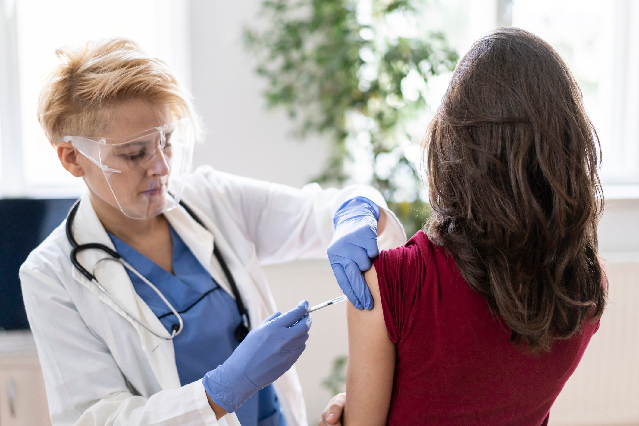 A healthcare worker vaccinates an individual in a medical office.