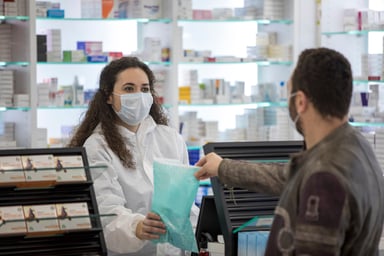 A pharmacist dispenses medication to a customer