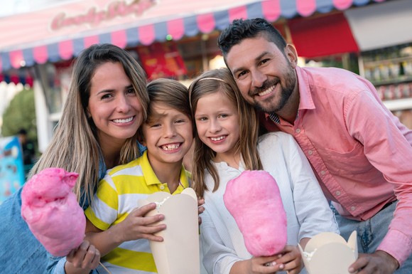 A family smiles while holding cotton candy.