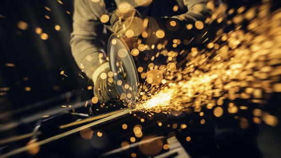 Sparks fly as an industrial worker uses a circular saw.
