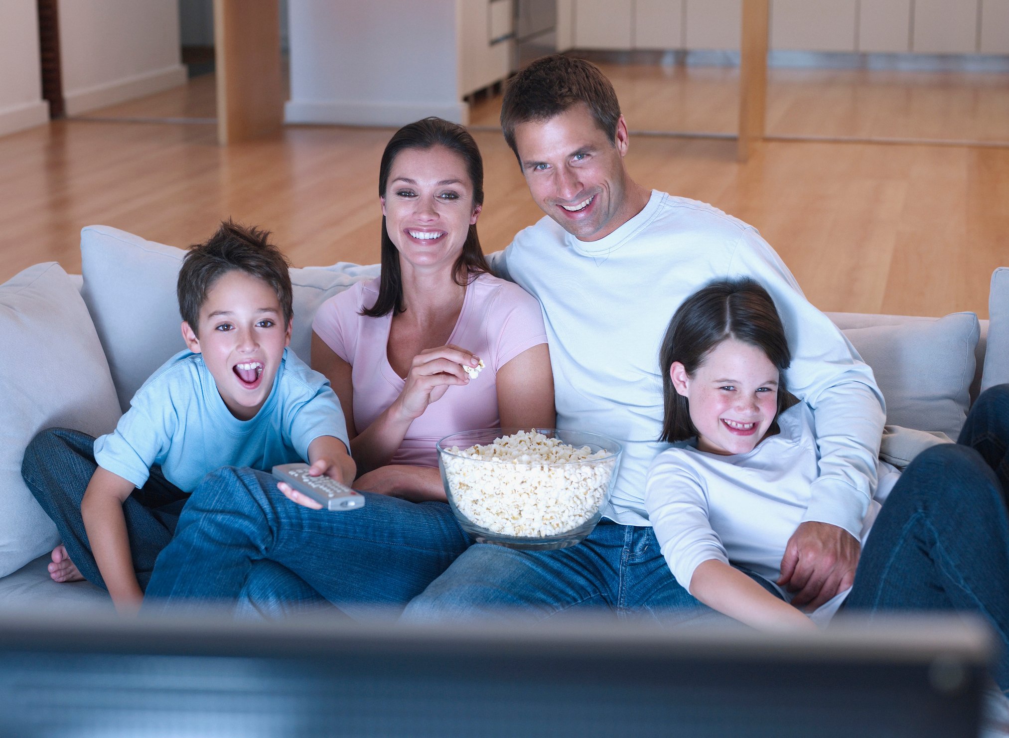 A family watching television and eating popcorn.