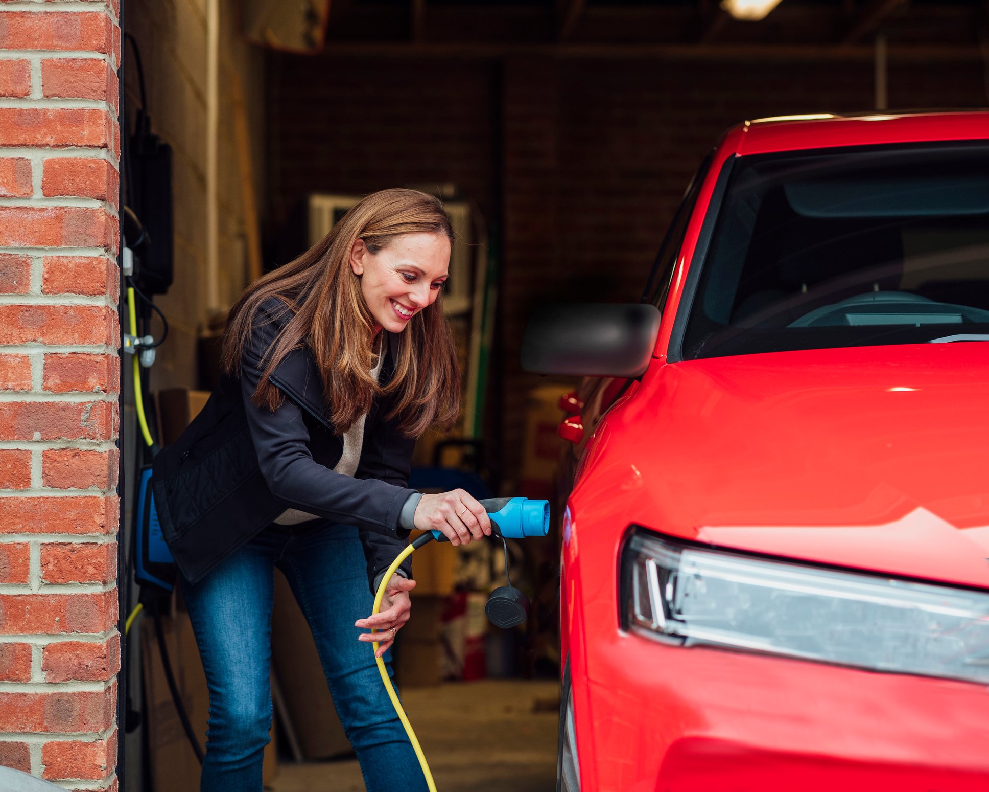 A person plugging a charger into an electric car.