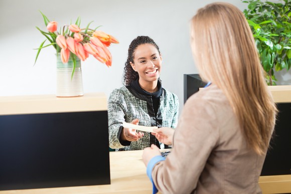 A bank teller takes a deposit from a customer.