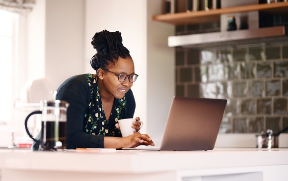 Person looking at laptop on kitchen counter.