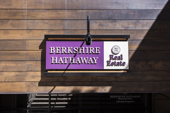 A Berkshire Hathaway Real Estate sign hangs against a wall.