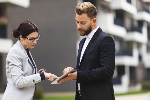 Two people agreeing to a digital contract on a tablet.