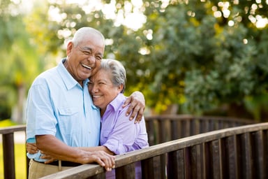 two older people standing outside hugging