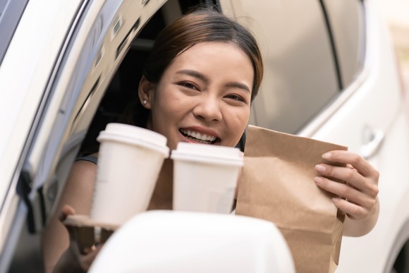 Person getting two coffees at a drive-thru window.
