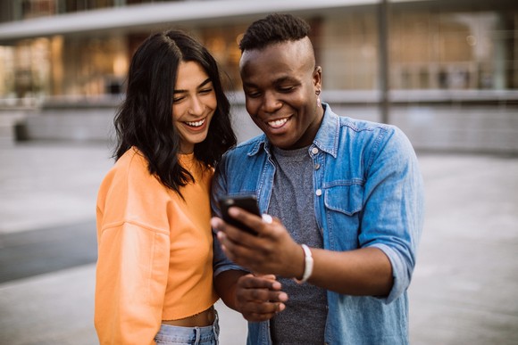 Happy couple outdoors staring at phone. 