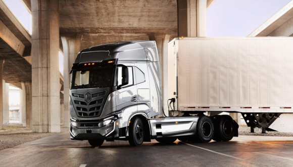 Nikola Tre battery electric semi truck with trailer under overpass. 