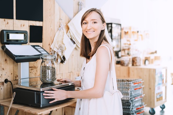 A worker in a cannabis dispensary weighs hemp seeds.