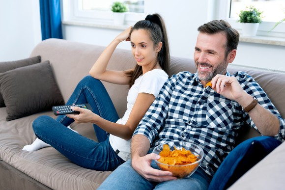 Two people on a couch watching TV.