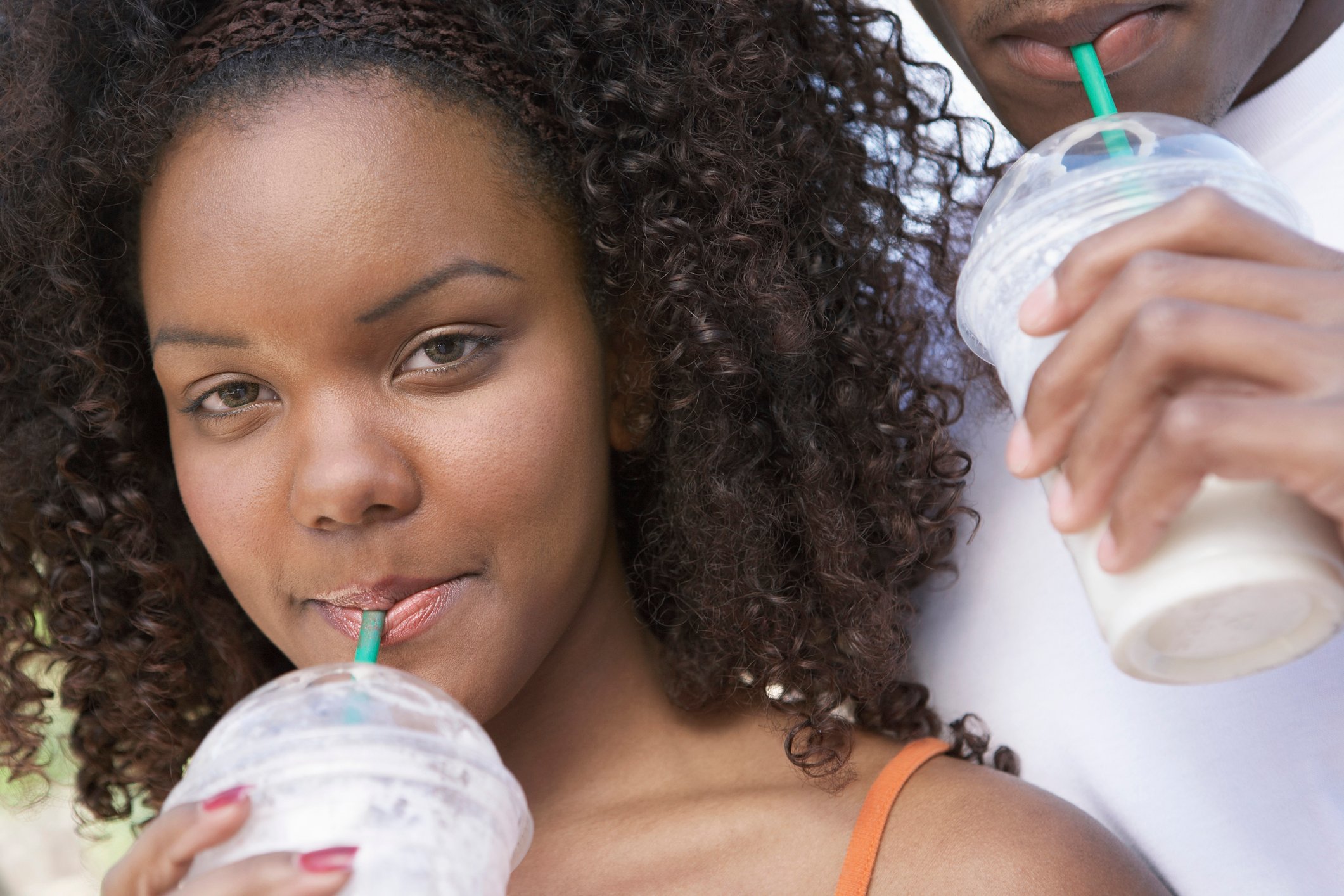 two people sipping cool beverages through straws