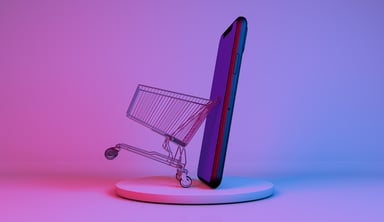 A miniature shopping cart next to a phone.