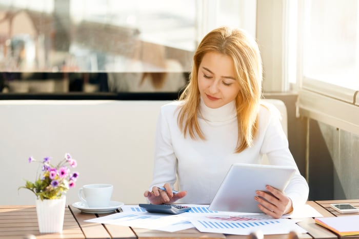 Une personne calcule des chiffres sur sa calculatrice pendant qu'elle examine des documents financiers.