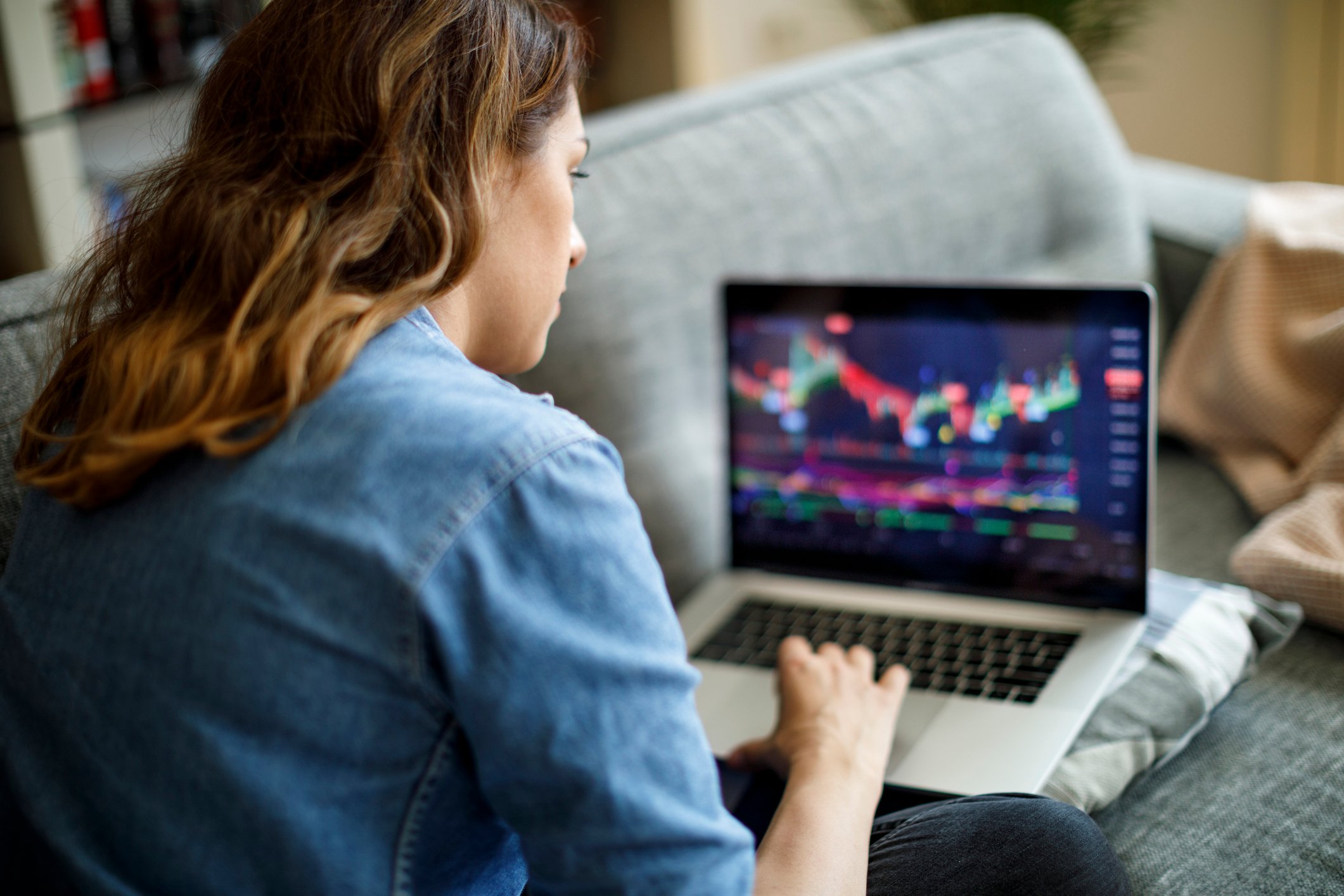 A person sitting on a couch researching stock market returns on a laptop. 