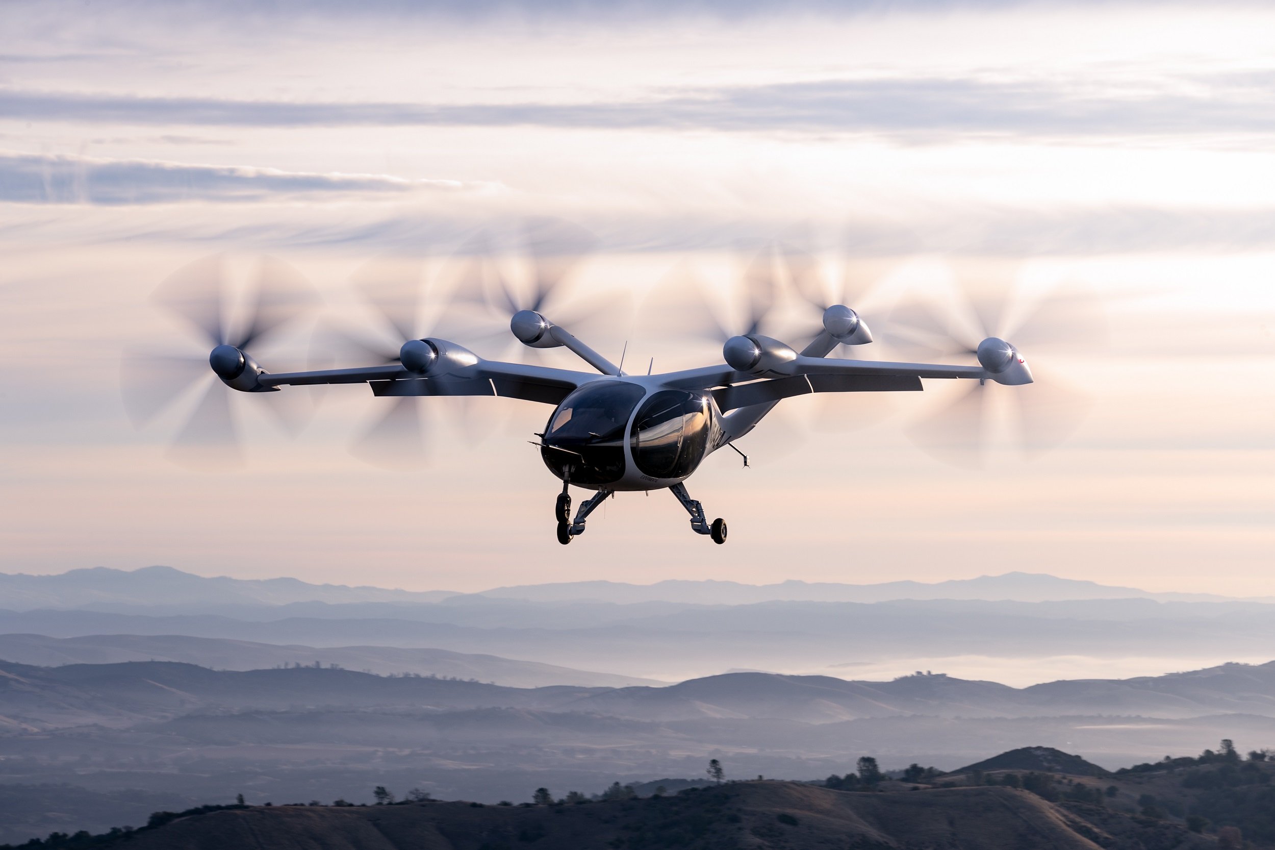 Joby's aircraft hovering over a mountain landscape.