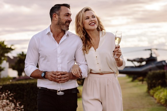 Two people walking in vineyard with glasses of champagne.
