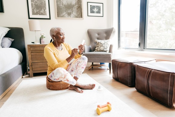 Person on mobile phone sitting in living room smiling.