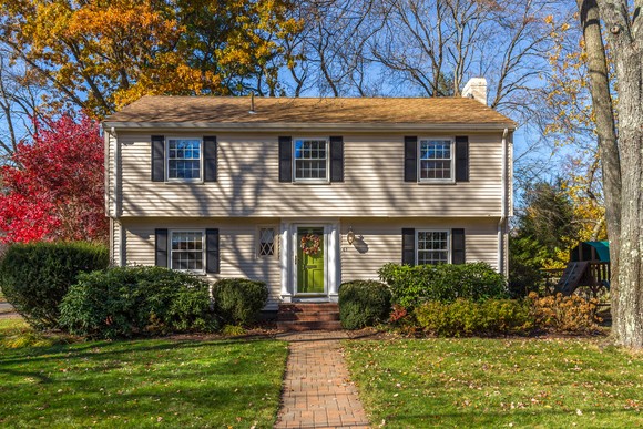 Two-story single-family house with green front door and trees changing colors.