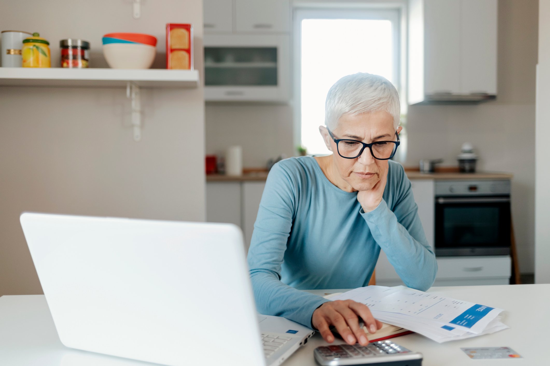 Person with laptop and calculator looking at paperwork.