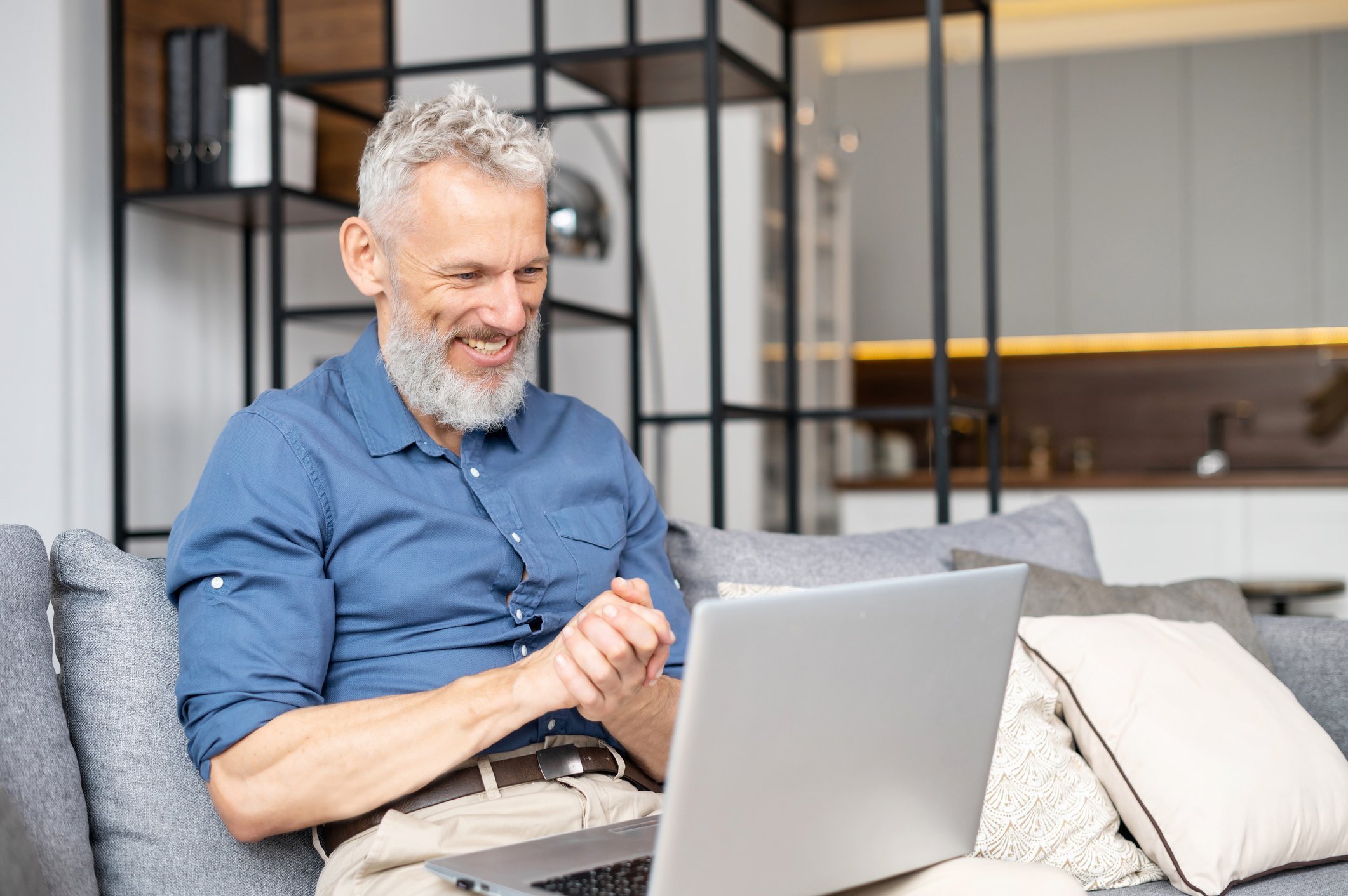 An older  person looking at a laptop and smiling.