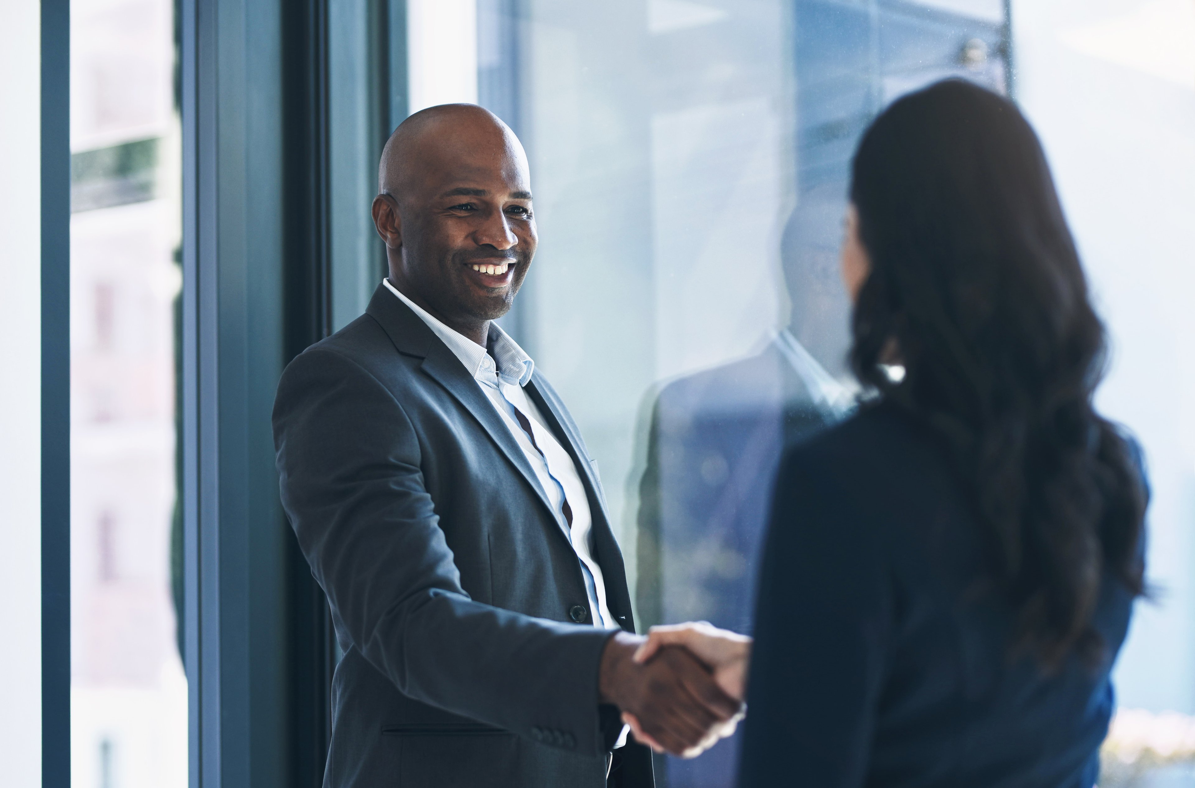 Two people in a corporate office building shake hands.