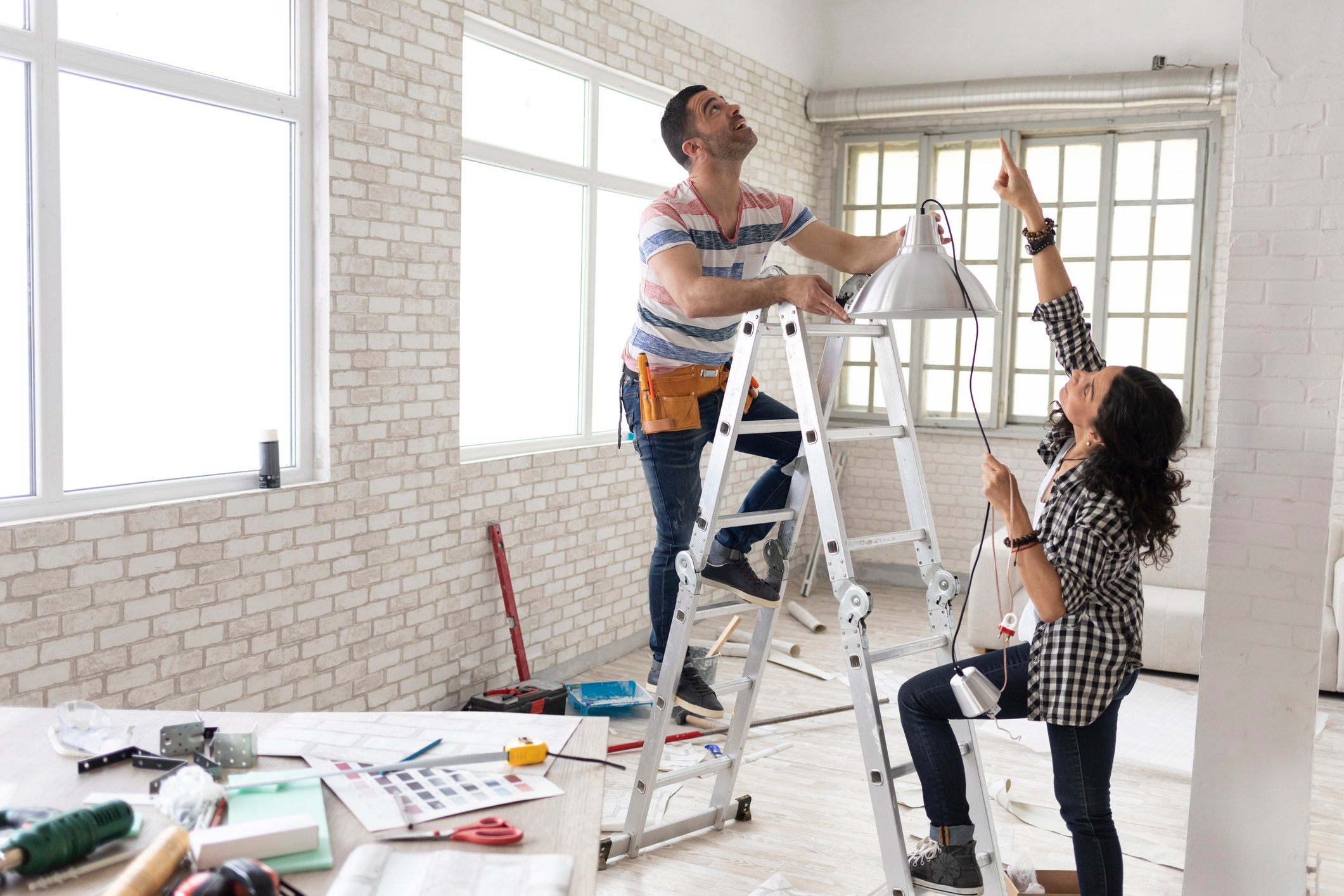 Two people installing a light fixture.
