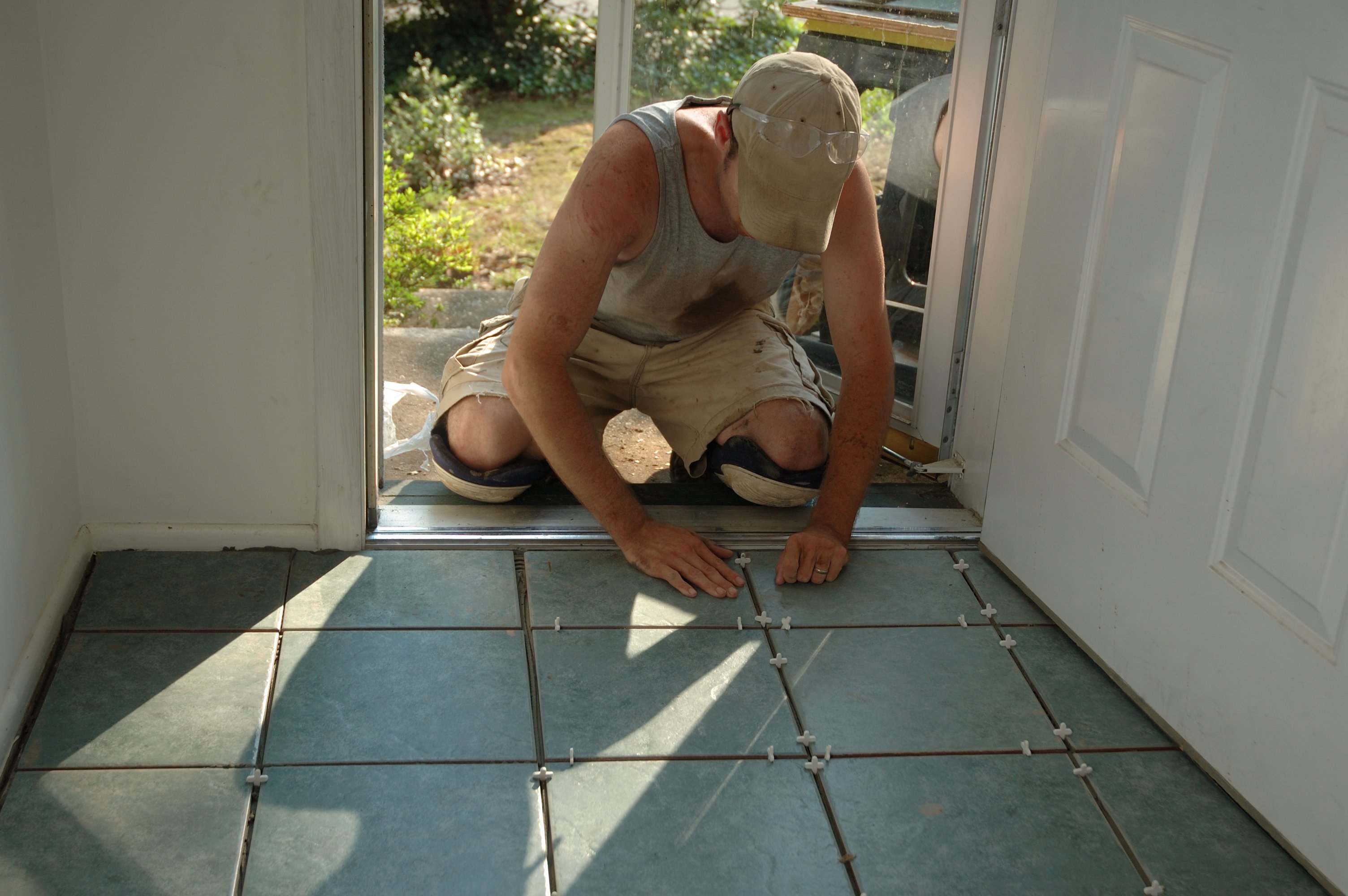 A person installing floor tiles.