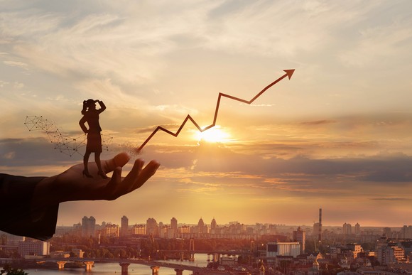 Person watching upward trending line set against a sunrise in a big city.