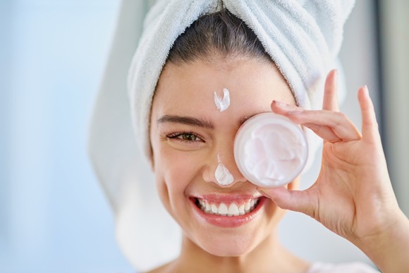 Person holding skin care product up to their face.